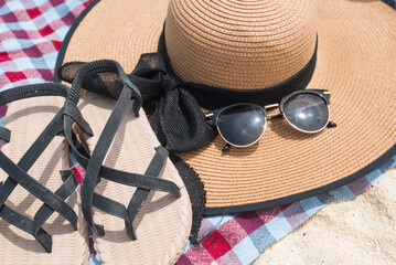 Close-up Slippers, Straw Hat, and Sunglasses on cotton. An accessory of the sea travel on a sandy beach. holiday summer relaxing and travel concept. The emotion of comfortable.