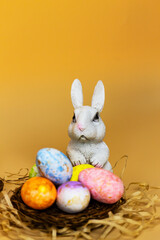 The brightly colored eggs surround a wicker basket placed on a straw bed. A scene celebrating Easter.