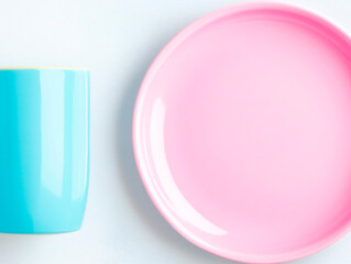 Bright pastel blue cup and pink ceramic plate on light background, minimal flat lay composition with glossy surface and playful color contrast