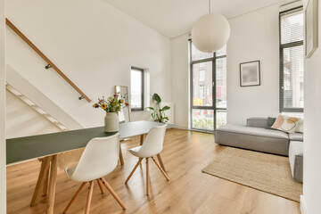 Bright and airy minimalist living room featuring a sleek dining table, comfortable sofa, and stylish decor elements in a contemporary setting.