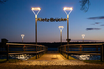 Kietz-Brücke (Kietz bridge) in Waren (Müritz) in the evening. Illuminated pier at the lake. Travel destination in Germany. Building exterior of the tourist attraction.