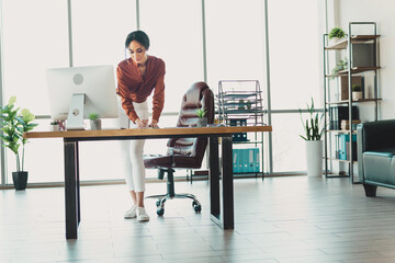 Professional businesswoman working in a modern open office with natural light and stylish decor...