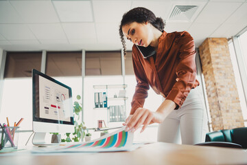 Focused young businesswoman multitasking at her desk in a modern bright office setting
