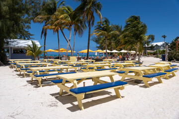 Rows of Colorful Yellow Picnic Tables on White Sandy Beach of Rum Point in Grand Cayman Island