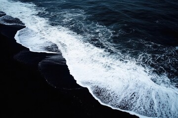 Fototapeta premium Dark Blue Ocean Waves Crashing on Black Volcanic Sand Beach Aerial View