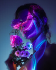 Artistic, captivating portrait of a woman partially illuminated by vibrant neon blue and purple lights, creating intriguing abstract patterns on her face and body. She gently holds delicate flowers