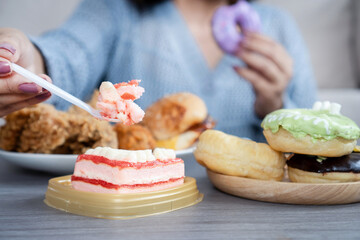woman dealing with binge eating disorder, eat a lot of fast food like burgers, fried chicken, donuts, and desserts, showing unhealthy eating habits and emotional stress related to food