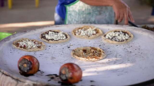 Woman spreading ingredients on traditional mexican sopes with spoon