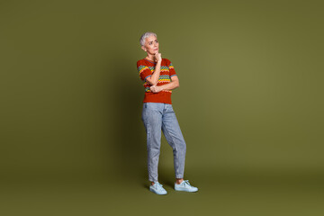 Fototapeta premium Trendy mature woman with short grey hair posing in casual outfit on khaki background showcasing fashion and lifestyle