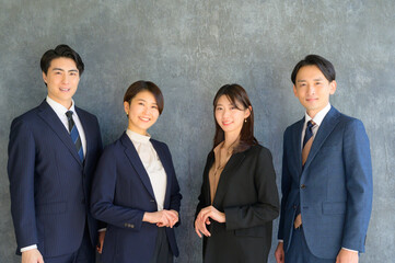4人で並んで笑顔の日本人ビジネスマン