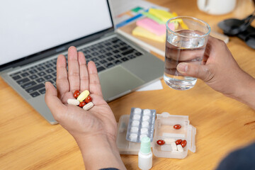 Rear view of a businessman taking pain relief medication after long hours of desk work