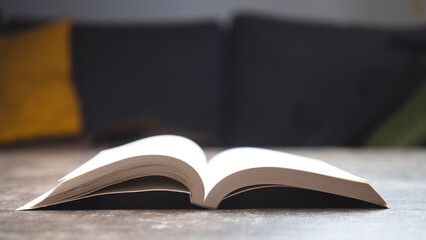Open book resting on a table in a cozy living space