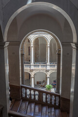 Wooden staircase descending towards elegant courtyard featuring columns
