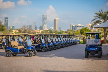 Golf carts lined up at luxury urban course, Dozens of blue golf carts parked outside a modern golf course with city.