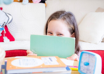 Schoolgirl. A 10-year-old Caucasian girl is doing her homework, smiling, and looking at the camera.