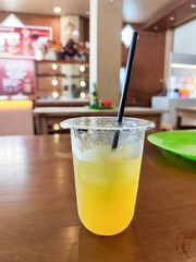 A glass of fresh cold orange ice on a table served in a traditional food stall.