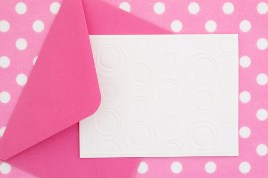 Blank greeting card and envelope on pink polka dots material