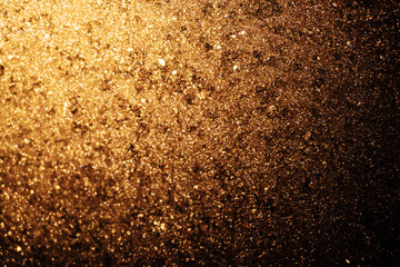 A close up of a gold and brown background with a lot of glitter. The background is a mix of gold and brown colors. Copy space.