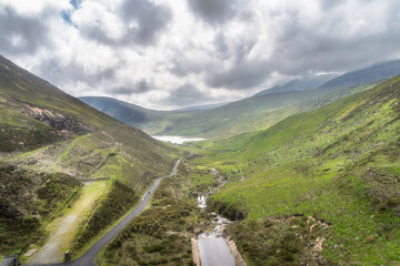 A stunning landscape featuring lush, vibrant green Silent Valley Reservoir and rolling hills of Mourn Mountains, offering a peaceful outdoor escape beneath a dramatic, cloudy sky, Northern Ireland