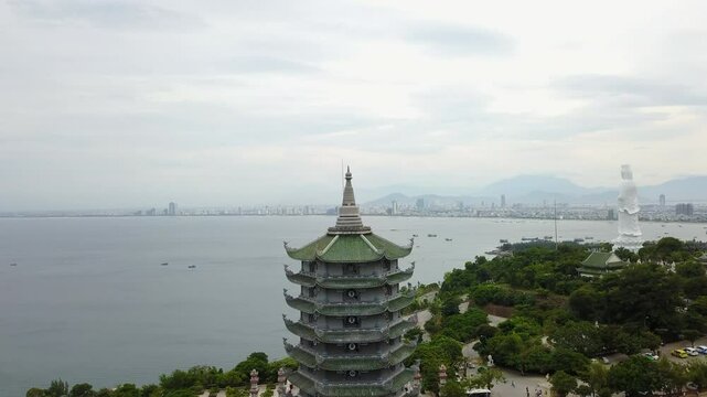 Aerial view featuring the Thap Xa Loi Temple and the distant Linh Ung Pagoda statue in the Da Nang region of Vietnam, showcasing Buddhist architecture and the coastal cityscape