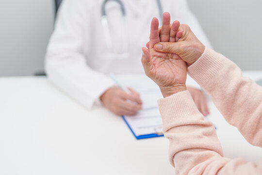 Senior woman having Tremor hand and consulting doctor in hospital. Parkinson disease April awareness month, Carpal Tunnel Syndrome, rheumatoid and brain injury and Neurological disorder concept - Powered by Adobe