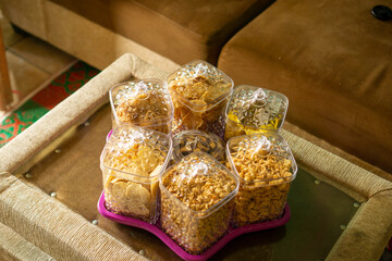 Traditional snacks in clear glass jars with lids, placed on a purple tray in a cozy living room.