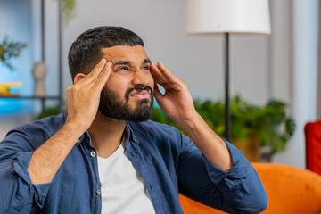 Sick Indian man rubbing temples to cure headache problem, suffering from tension and migraine...