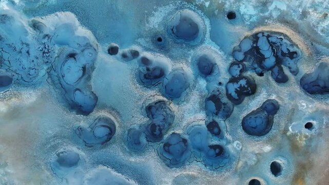 Bird&rsquo;s-eye view of a surreal geothermal landscape at Hverir, Iceland, with steaming vents, textured mud crusts, and mineral contrasts.
