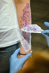 Tattoo Artist Applying Stencil on Arm for Ink Design
