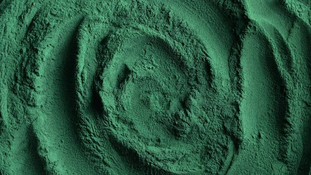 Heap of green spirulina algae powder spins, close up. Green powder super food, macro, rotation. Dietary supplement to improve health. Seaweed superfood concept. Healthy food background