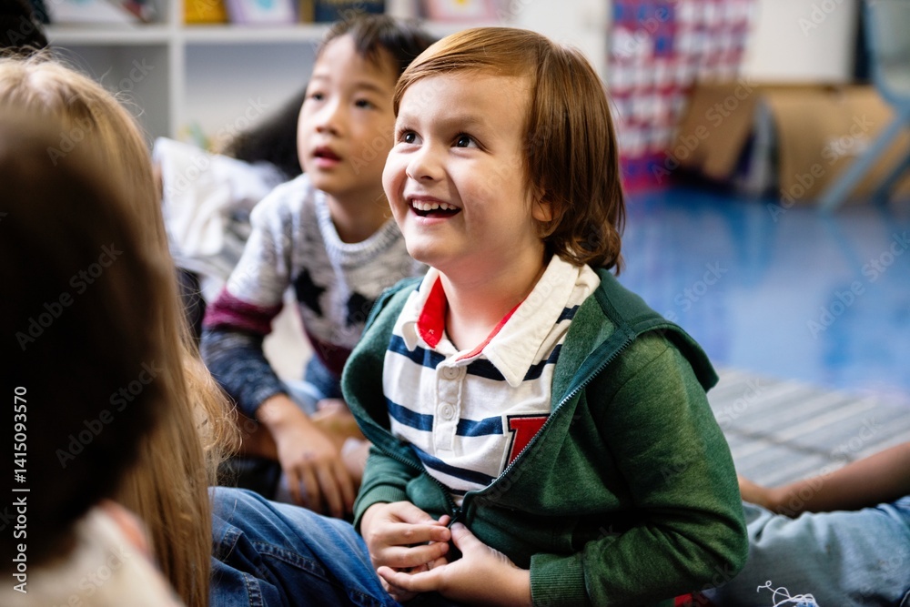 Poster happy caucasian boy smiling and sitting with other children in classroom. boy in classroom with othe
