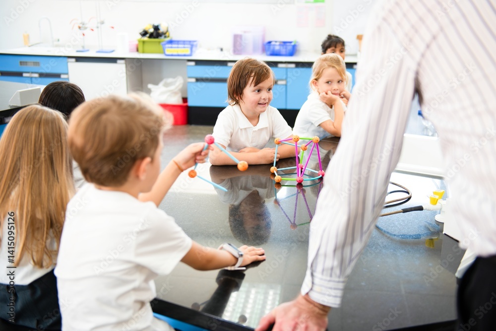 Poster Children in a science classroom, engaged in learning. Kids explore science with models. Teacher guides students in a science activity. Classroom learning environment. Students listening to teacher.