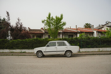 A small white car parked on a street in a Turkish village.