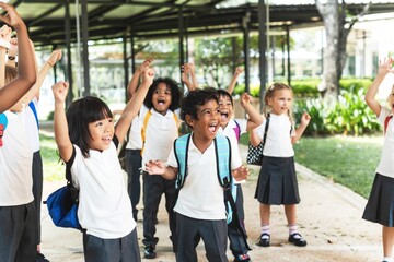 Group of diverse children in elementary school uniforms. Diverse elementary students with backpacks, joyful and playful Diverse school kids enjoying a sunny day at school together.