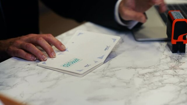 Customs worker stamping approved seal in UK passport, entry permission granted