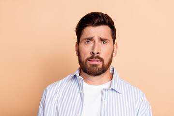 Obraz premium Portrait of a Young Man With Beard and Casual Outfit Expressing a Surprised Facial Gesture in Front of a Neutral Beige Background