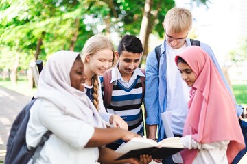 Diverse group of students study outdoors, group project. Diverse students engage in learning, outdoor activity. Group of young students with books. Outdoor study session with diverse student group