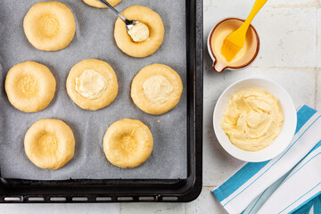 Cooking sweet ricotta buns, homemade yeast dought with cream filling, brioche, kalacs, or vatrushka on a cooking tray. Directly above.