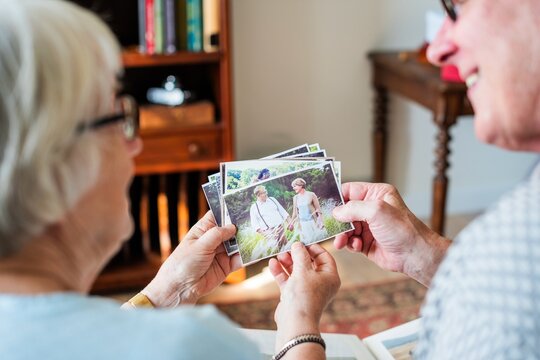 Elderly couple looking at old photos, reminiscing. The couple enjoys memories, sharing stories. Photos bring nostalgia and connection to the elderly pair. Elderly couple looking at photos at care home