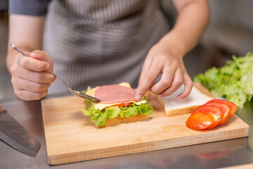 Smiling Young Female Chef Preparing a Sandwich in a Professional Kitchen