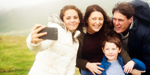 Fototapeta premium Happy family taking selfie outdoors while traveling. Family, mother, father, daughter, and son, selfie together. Family selfie outdoor. Family enjoy their trip outdoor. Happy family taking selfie