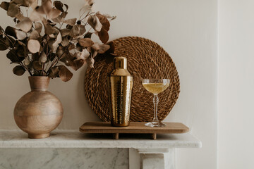 Elegant Home Bar Setup with Golden Shaker and Champagne Glass on Mantel