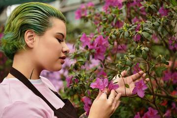 Fototapeta premium Young woman tending to vibrant flowers in a lively greenhouse with a passion for gardening