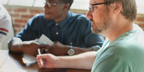 Business men in a meeting, one holding a tablet. The men are focused, engaged in business discussion. Team meeting with office workers in startup business. Startup business meeting.