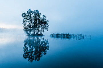 Dawn breaks over an island with trees in Finnsjön lake near Gothenburg, Sweden, creating a serene...