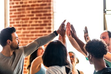 Group of diverse people high-fiving indoors. Teamwork and celebration. Smiling individuals in...