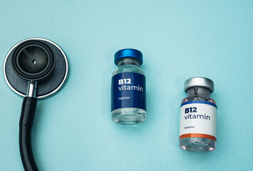 A stethoscope lies beside two vials of B12 vitamin injection. Health and medical concept