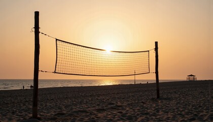 Beach volleyball net silhouetted against sunset at shoreline  