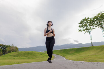 A joyful young woman jogging through a public park with a smile on her face.