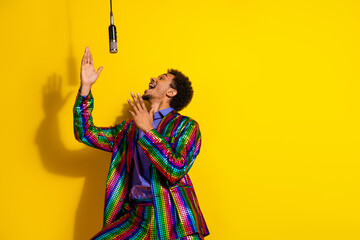 Young charismatic man wearing vibrant suit sings passionately in a dynamic studio setup with yellow...